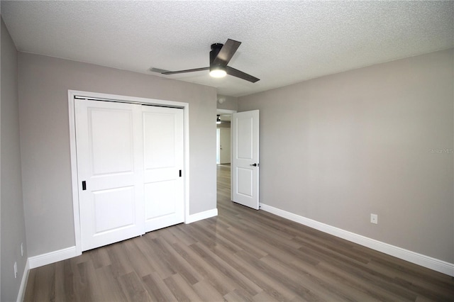 unfurnished bedroom featuring dark hardwood / wood-style floors, a textured ceiling, a closet, and ceiling fan