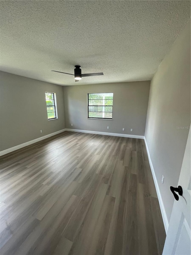 empty room with dark hardwood / wood-style floors, a textured ceiling, and ceiling fan