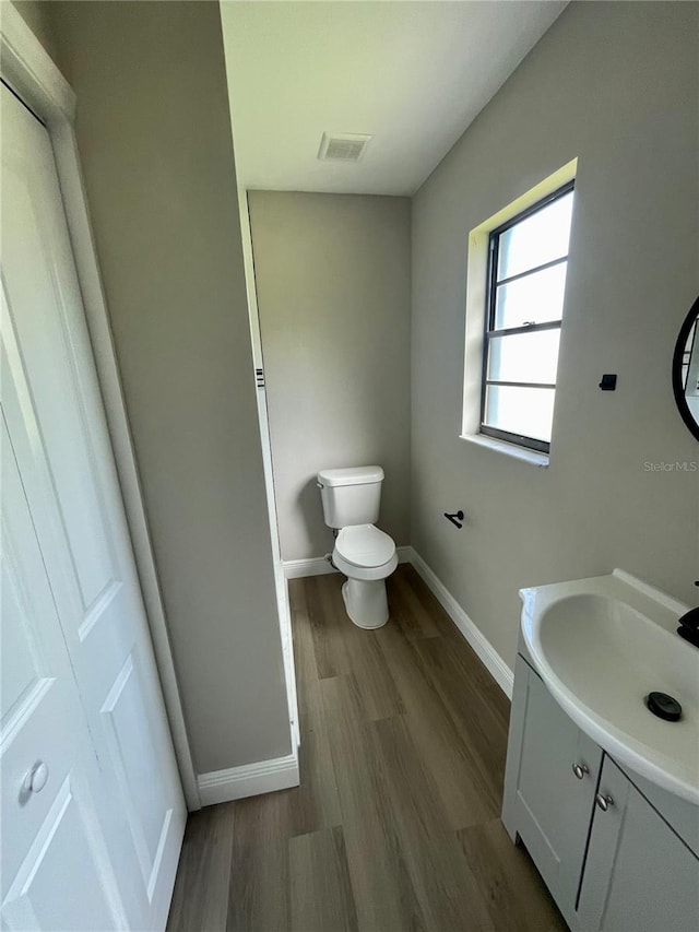 bathroom with toilet, vanity, and hardwood / wood-style flooring