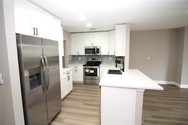 kitchen with white cabinetry, backsplash, light wood-type flooring, and stainless steel appliances