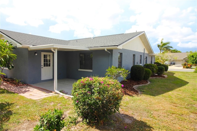 view of side of home featuring a lawn and a patio area