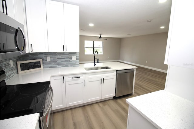 kitchen featuring stainless steel appliances, light hardwood / wood-style flooring, white cabinetry, backsplash, and sink