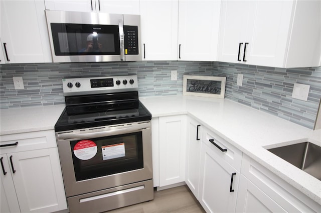 kitchen with tasteful backsplash, light stone counters, appliances with stainless steel finishes, and white cabinetry