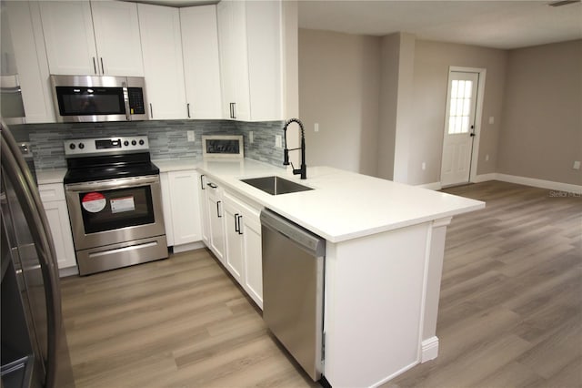 kitchen featuring kitchen peninsula, backsplash, light hardwood / wood-style floors, sink, and stainless steel appliances