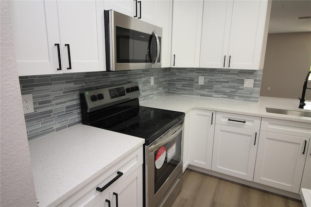 kitchen featuring backsplash, dark hardwood / wood-style floors, white cabinetry, and appliances with stainless steel finishes