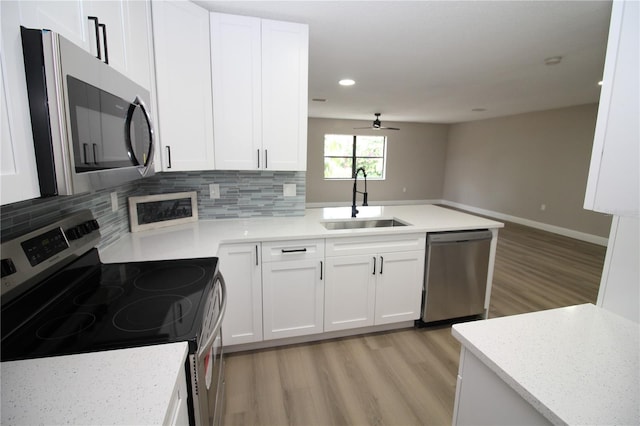 kitchen featuring sink, white cabinets, backsplash, stainless steel appliances, and light wood-type flooring