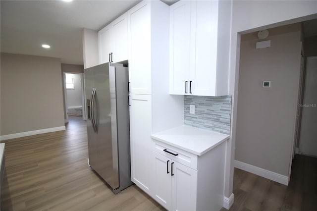 kitchen featuring stainless steel fridge, wood-type flooring, and white cabinets