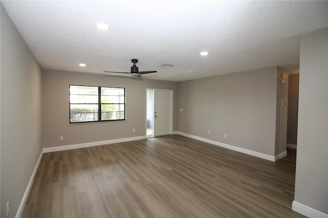 empty room with ceiling fan, a textured ceiling, and dark wood-type flooring