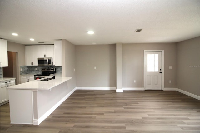 kitchen with white cabinetry, light hardwood / wood-style floors, stainless steel appliances, a textured ceiling, and tasteful backsplash