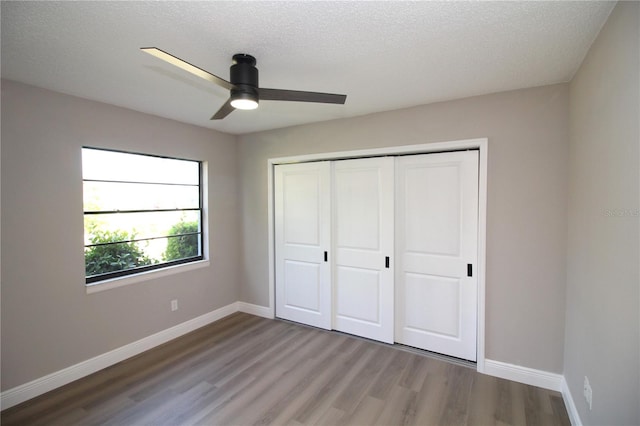 unfurnished bedroom featuring a textured ceiling, dark hardwood / wood-style flooring, a closet, and ceiling fan