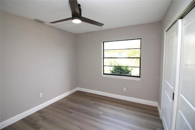 spare room featuring ceiling fan, a textured ceiling, and dark wood-type flooring