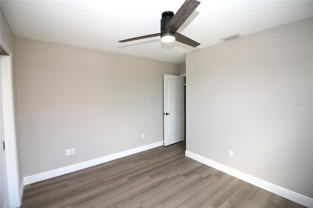 empty room featuring a textured ceiling, ceiling fan, and dark wood-type flooring