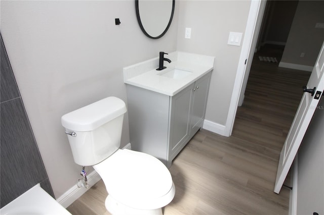 bathroom with toilet, vanity, and hardwood / wood-style flooring