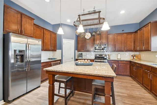 kitchen with a kitchen bar, light hardwood / wood-style floors, tasteful backsplash, and stainless steel appliances