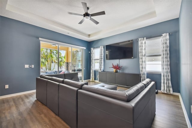 living room featuring ceiling fan, a textured ceiling, dark hardwood / wood-style floors, and a raised ceiling