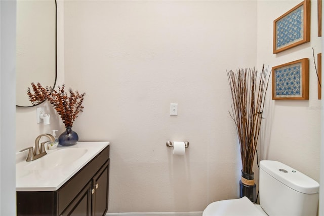 bathroom with toilet and vanity with extensive cabinet space