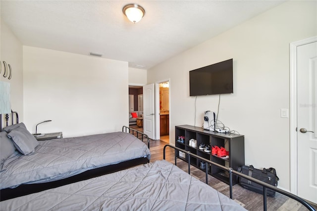 bedroom featuring ensuite bathroom and wood-type flooring