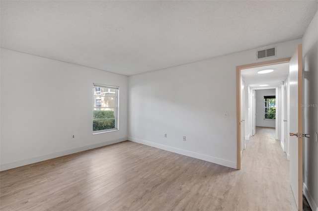 empty room with light hardwood / wood-style floors and a textured ceiling