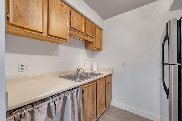 kitchen featuring stainless steel fridge, light wood-type flooring, and sink