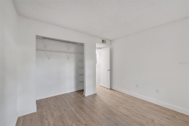 unfurnished bedroom with a closet, a textured ceiling, and light hardwood / wood-style floors