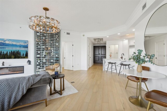 living room featuring ornamental molding, light hardwood / wood-style flooring, and sink