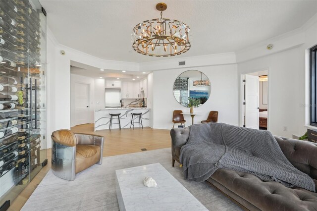 living room featuring ornamental molding, light hardwood / wood-style flooring, and an inviting chandelier