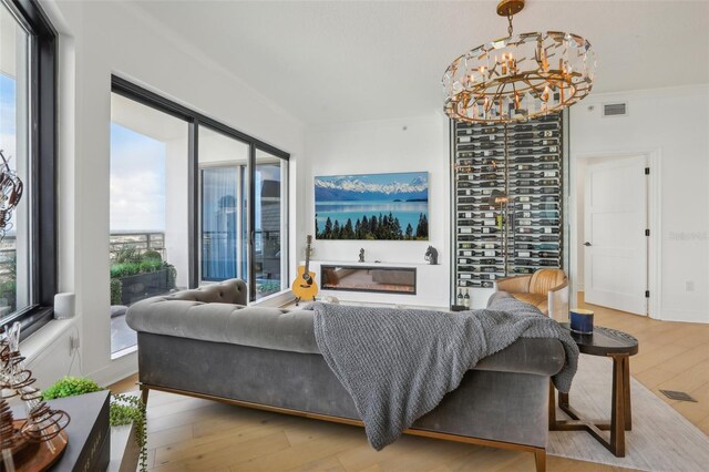 living room featuring light wood-type flooring, a fireplace, and an inviting chandelier