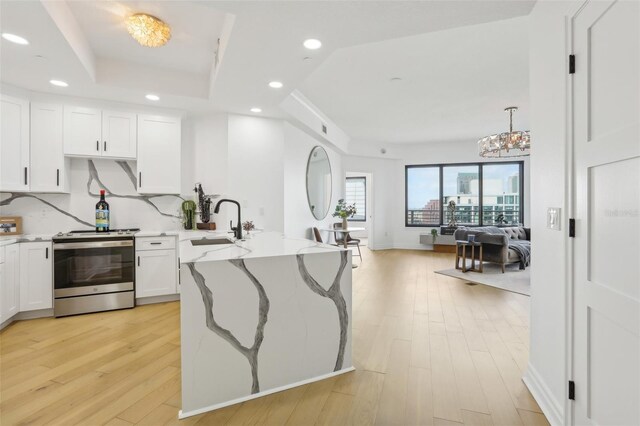 kitchen with a chandelier, stainless steel range, light wood-type flooring, and white cabinetry