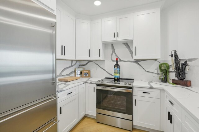 kitchen featuring white cabinets, light stone countertops, stainless steel appliances, and decorative backsplash