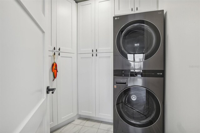 washroom with cabinets and stacked washing maching and dryer