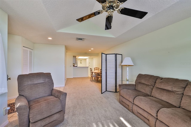 living room featuring light carpet, a textured ceiling, and ceiling fan