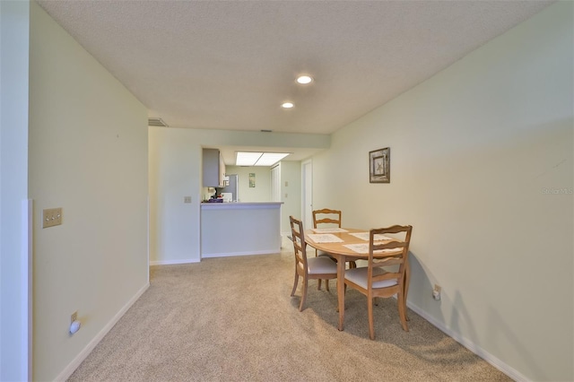 dining area with a textured ceiling and light colored carpet