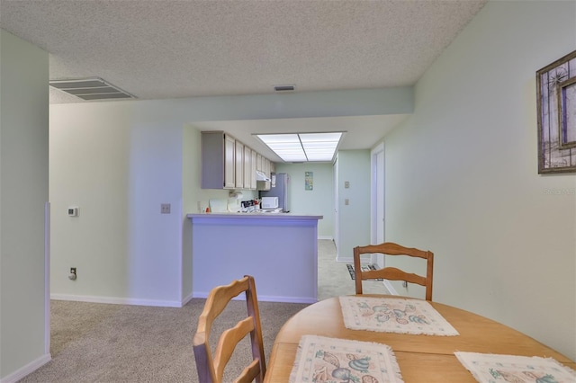 dining area with light carpet and a textured ceiling