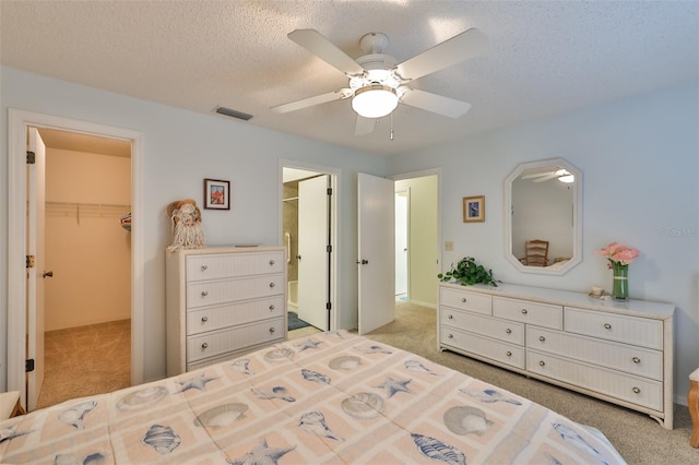 bedroom featuring ensuite bath, a spacious closet, light colored carpet, and ceiling fan