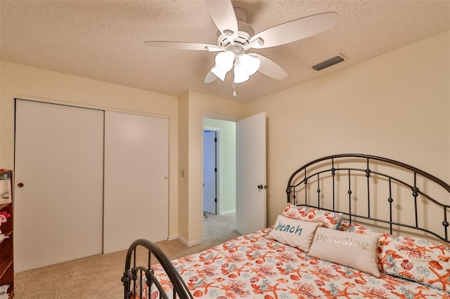 carpeted bedroom with a textured ceiling, a closet, and ceiling fan