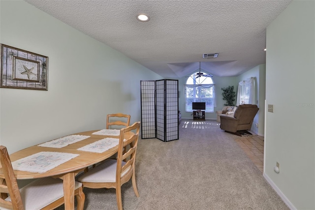 dining space with a textured ceiling, light colored carpet, and lofted ceiling