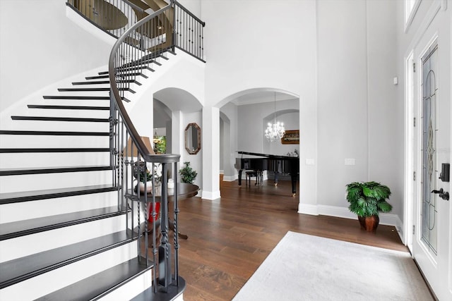 entrance foyer with a notable chandelier, a towering ceiling, and dark hardwood / wood-style floors