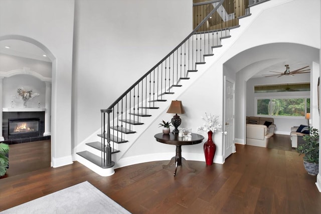 stairway featuring a towering ceiling, wood-type flooring, and a tile fireplace