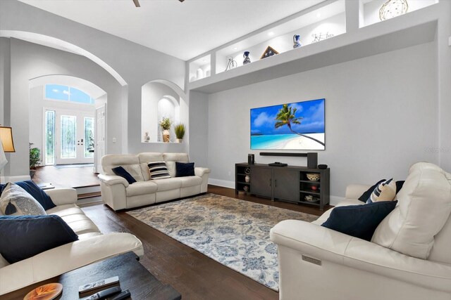 living room featuring baseboard heating, dark hardwood / wood-style flooring, and a high ceiling