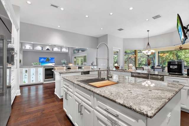 kitchen featuring appliances with stainless steel finishes, white cabinetry, light stone counters, a kitchen island, and dark hardwood / wood-style flooring