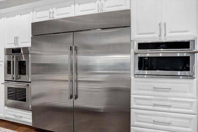 kitchen featuring white cabinetry, appliances with stainless steel finishes, and dark hardwood / wood-style flooring