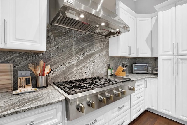 kitchen with white cabinets, decorative backsplash, stainless steel gas cooktop, exhaust hood, and light stone countertops