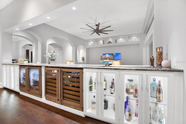 bar featuring wine cooler, stone countertops, dark hardwood / wood-style floors, and white cabinets