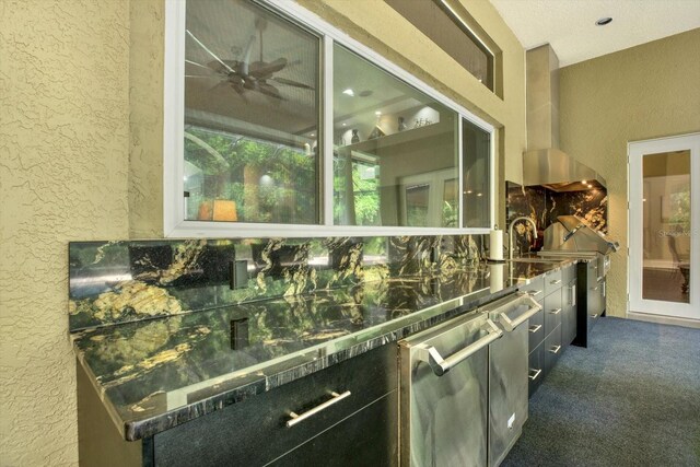 exterior space with dark stone countertops, dark carpet, and wall chimney range hood