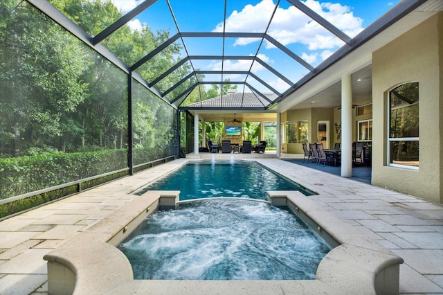 view of swimming pool with an in ground hot tub, a patio, ceiling fan, and glass enclosure