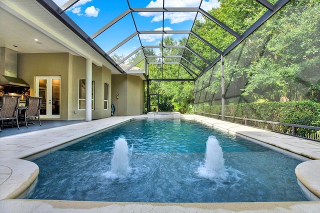 view of pool with pool water feature, a patio area, glass enclosure, and french doors