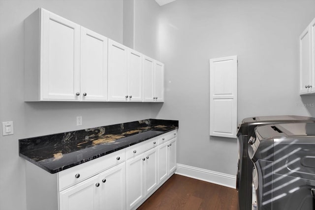 kitchen with dark hardwood / wood-style floors, washer and clothes dryer, and white cabinets