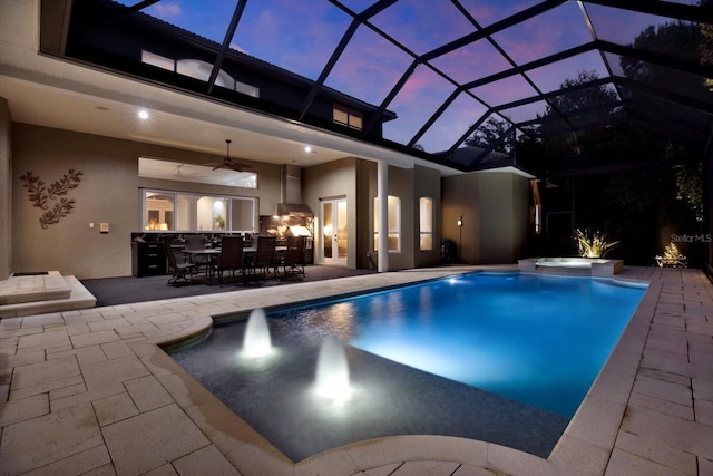 pool at dusk with an in ground hot tub, a patio, ceiling fan, and glass enclosure