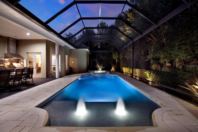 pool at dusk with french doors, grilling area, glass enclosure, an in ground hot tub, and a patio