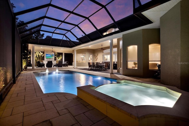 pool at dusk featuring ceiling fan, a patio area, and glass enclosure